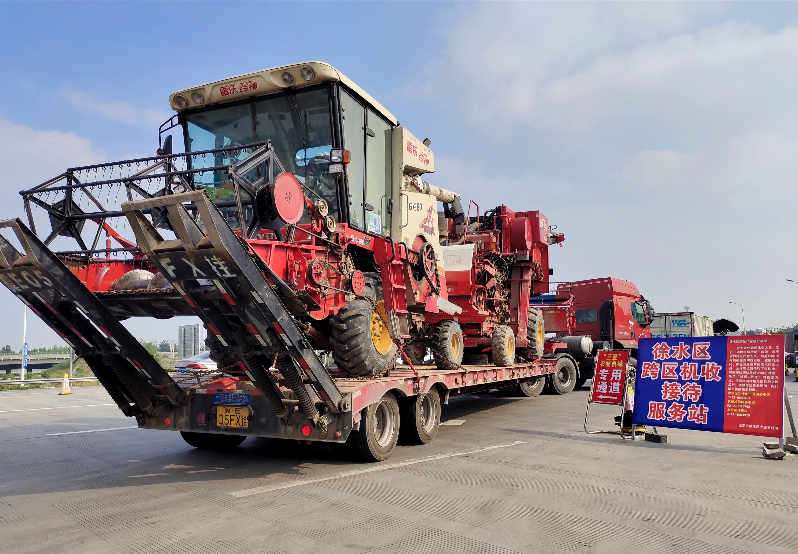 裝載兩輛收割機的大貨車駛出京港澳高速徐水出口。李月英 攝